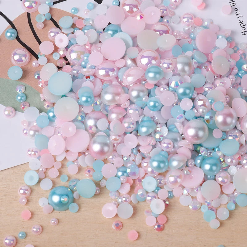 A pile of mixed resin rhinestone pearls in various shades of pink and blue with an AB finish for crafts and nail art.
