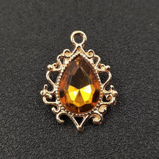 Gold plated water droplet charm featuring a faceted amber crystal rhinestone set in an ornate flower design.