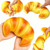 Hands are squeezing a yellow squishy croissant stress relief toy.