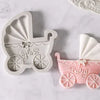 A set of white silicone baby-themed cake molds including a stroller, bottle, and pacifier in pink and white.