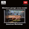 A miniature garage scene model depicting an American workshop with cars and figures inside a display cabinet.
