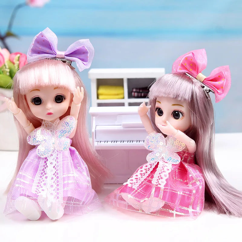 A pink articulated princess doll with a purple bow and a pink sparkly dress sitting in front of a white piano.