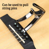A silver tool is shown pulling string pins from a guitar fretboard.