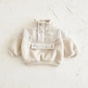 A cream colored toddler fleece-lined winter coat with a half-zip closure and fluffy trim.