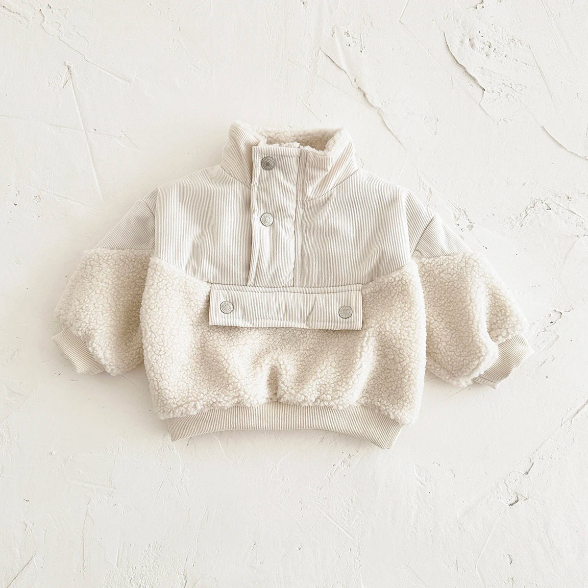 A cream colored toddler fleece-lined winter coat with a half-zip closure and fluffy trim.