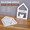 A white silicone mold set for creating house, heart, and Christmas ornaments on a wooden surface.