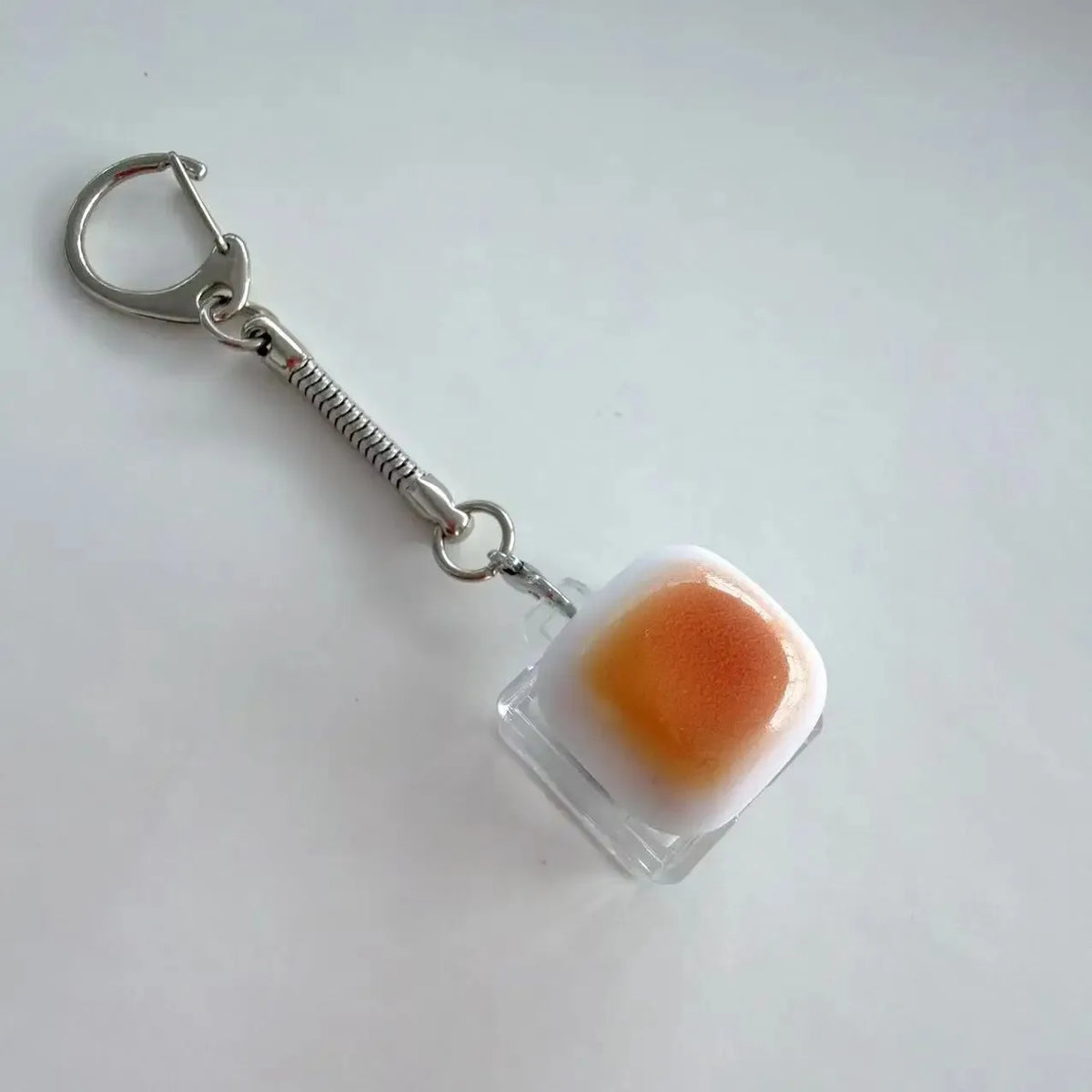Silver chain keychain featuring an orange and white translucent keycap.