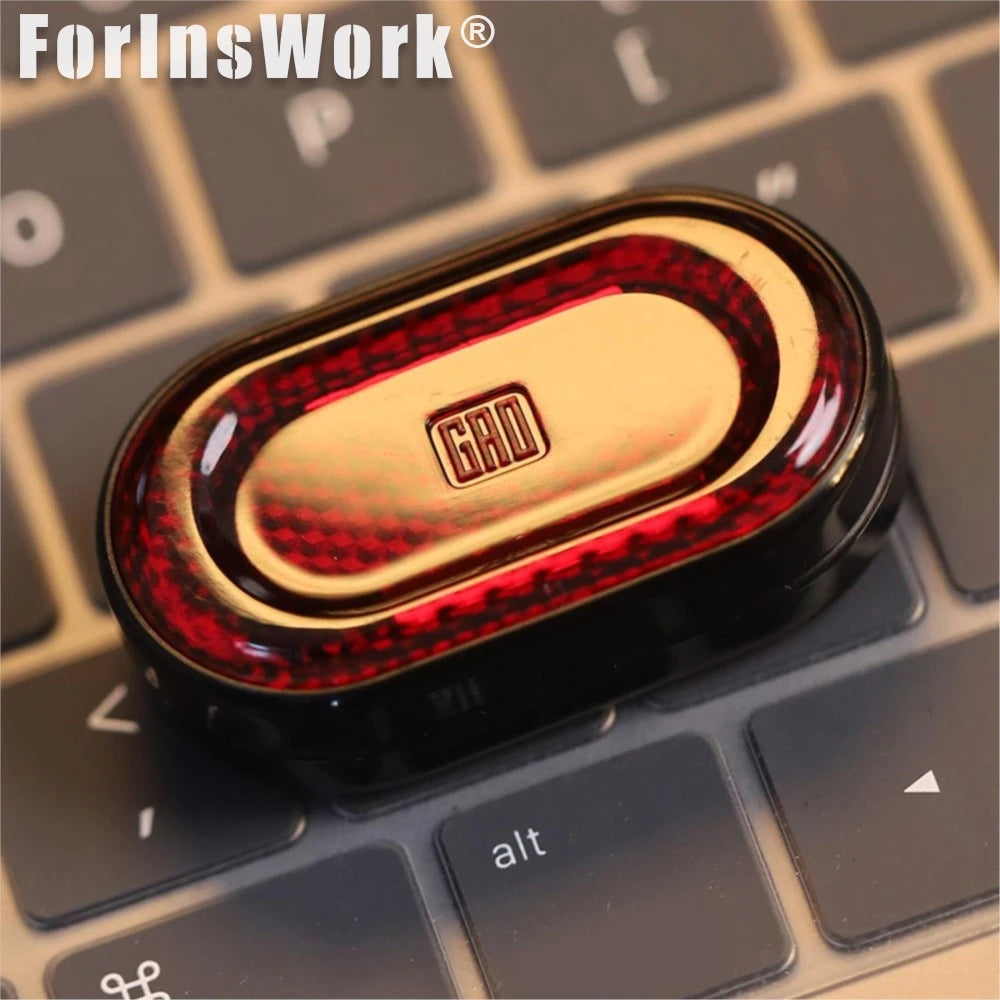 A close-up of a metallic fidget slider with a red and gold gem design resting on a keyboard.