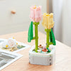 A set of pink and yellow rose flower building blocks arranged in a bouquet on a wooden table.