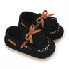 Pair of black baby first walker sneakers with brown ribbon ties and white stitching