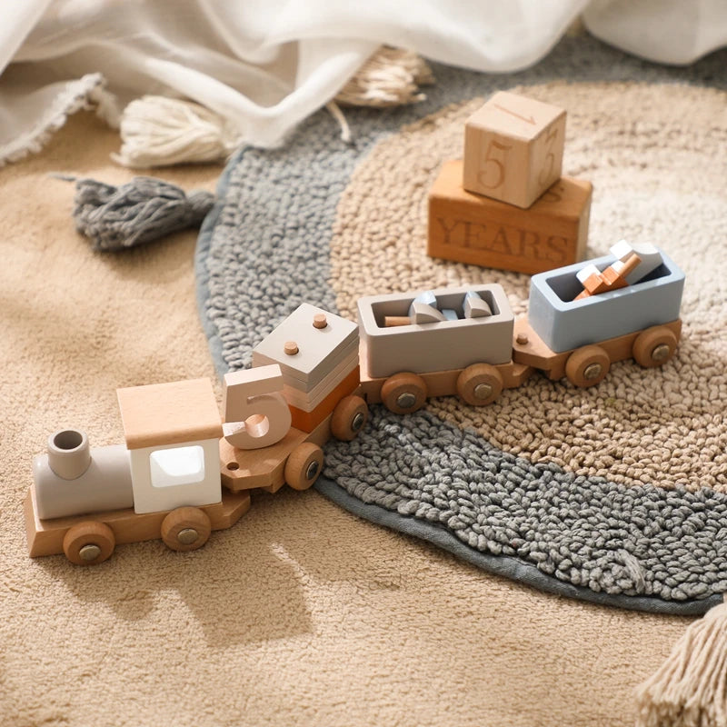 A wooden train toy carrying glass beads and labeled blocks on a textured beige surface.