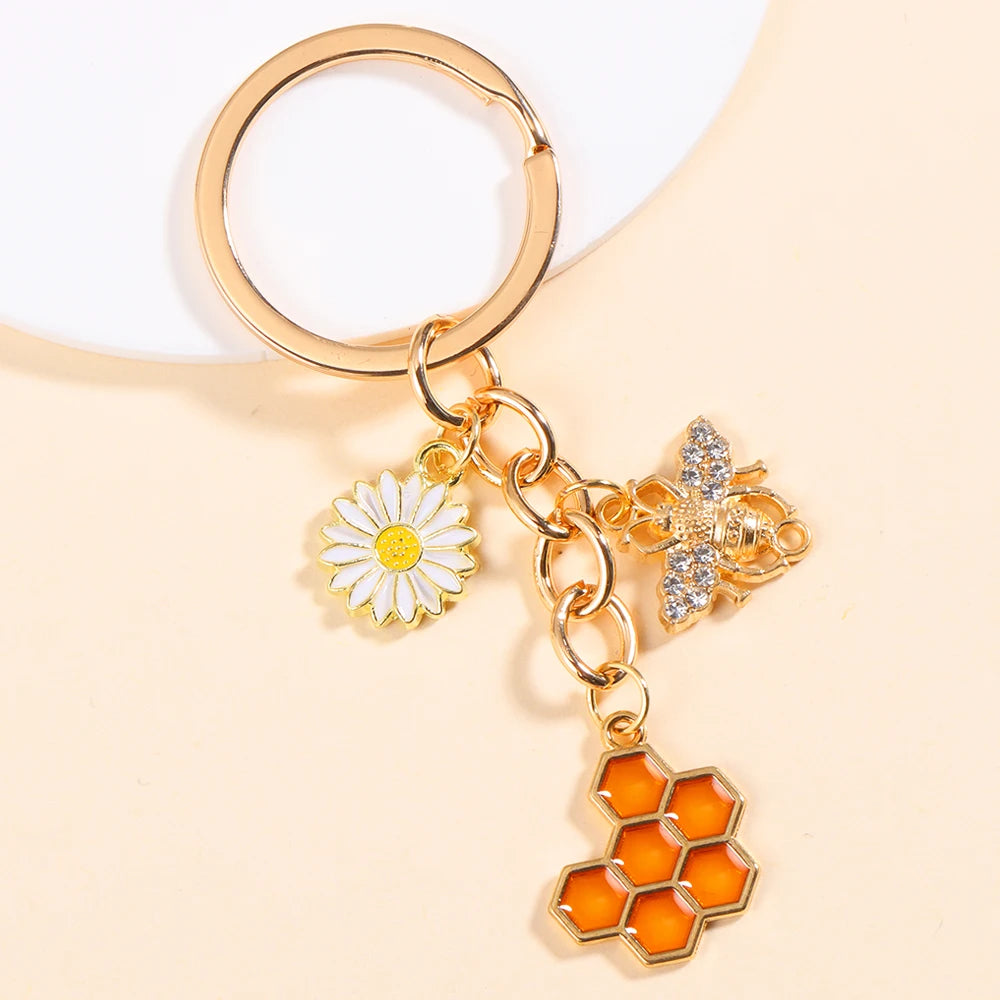 Gold enamel flower keychain featuring a daisy and an orange honeycomb charm