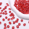 A pile of red gradient tulip glass beads is shown in a white ceramic container.