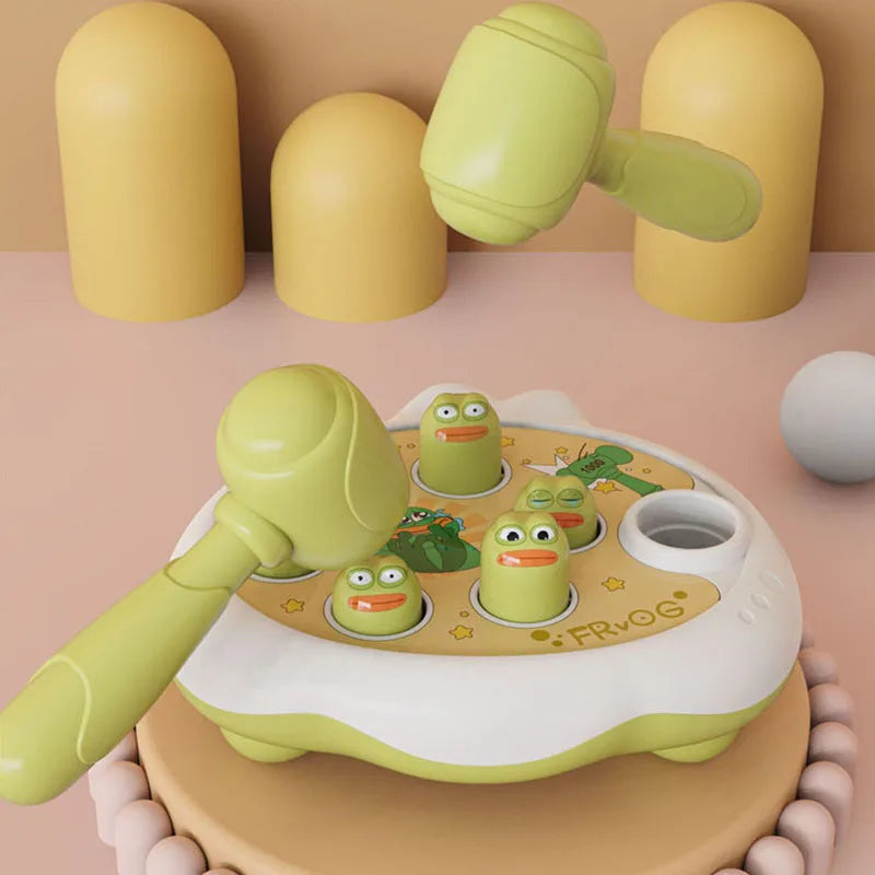 A green and yellow Montessori animal hammer toy with various plastic parts is shown on a light wooden surface.