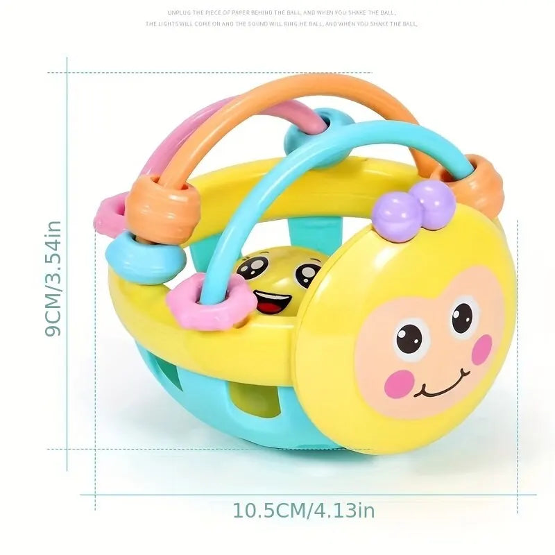 A yellow sensory catch ball rattle toy with pink and blue accents shown from above.