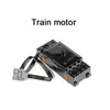 A black train motor with wires and connectors is shown.