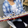 A detailed model kit of the Bismarck Battleship built from plastic blocks, held by a person.