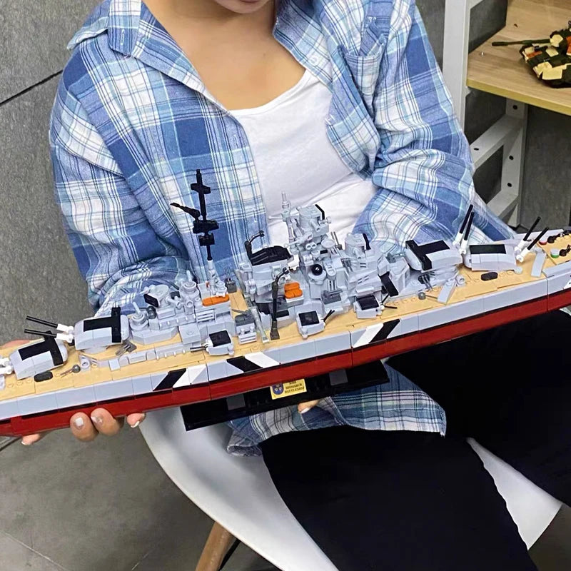 A detailed model kit of the Bismarck Battleship built from plastic blocks, held by a person.