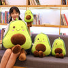 A person is sitting on a couch with several cute, bright green avocado plush toys.