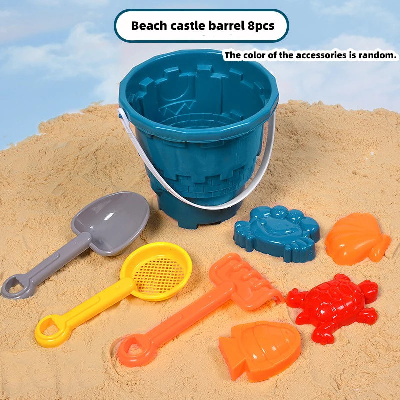 E acht Küstenburg-Fässer und verschiedene orange und blaue Sandgrabwerkzeuge liegen auf Sand.