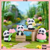 A set of cute panda collectible figures in various colors and poses displayed in a lush green garden setting.