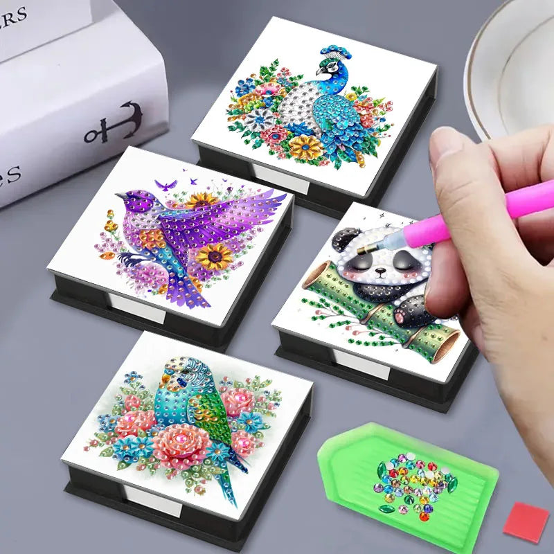 A collection of DIY diamond painting animal patterns, including a peacock and a panda, displayed in storage boxes.