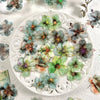A plate filled with floral hot stamp stickers featuring various shades of green, blue, and purple flowers.