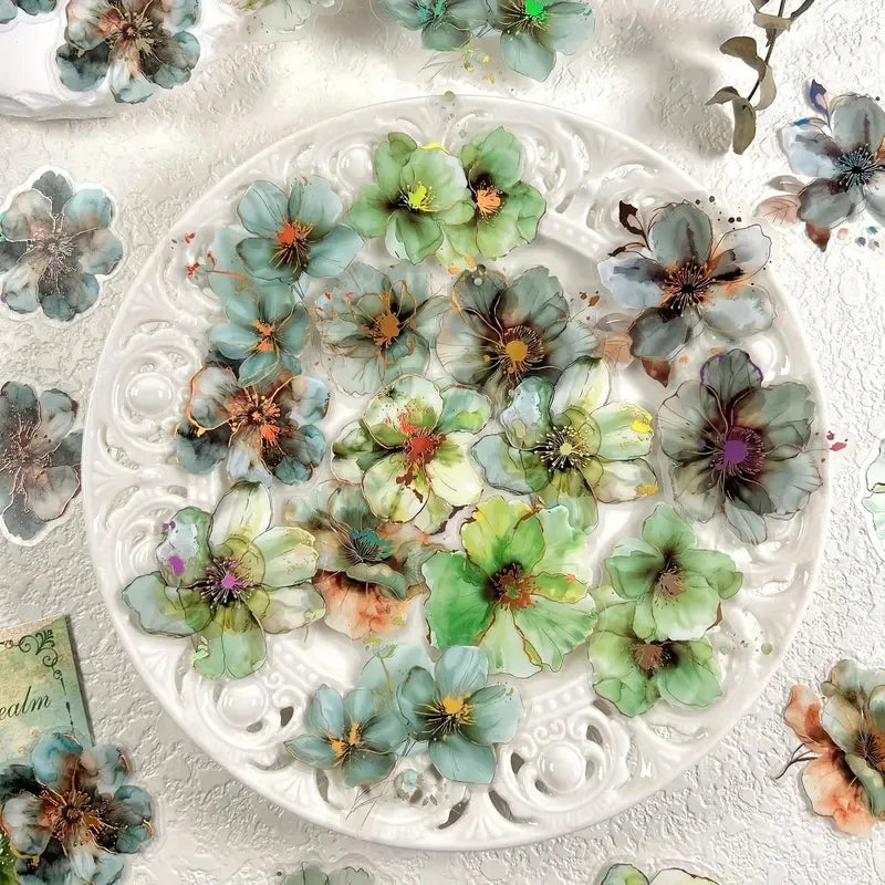 A plate filled with floral hot stamp stickers featuring various shades of green, blue, and purple flowers.