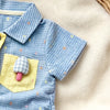 A baby boy short-sleeve romper in blue gingham with yellow appliqués of a bear and mushroom on a cream fabric background.