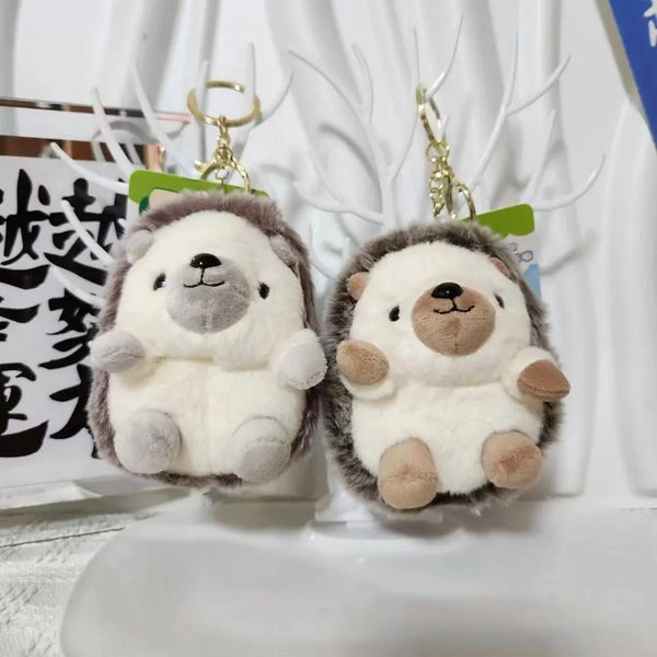Two fluffy bear-shaped keychains with gray and white fur hanging from gold-colored clasps.