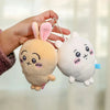 A hand holds a soft, light brown Chiikawa Usagi plush keychain charm with pink ears and a white version.