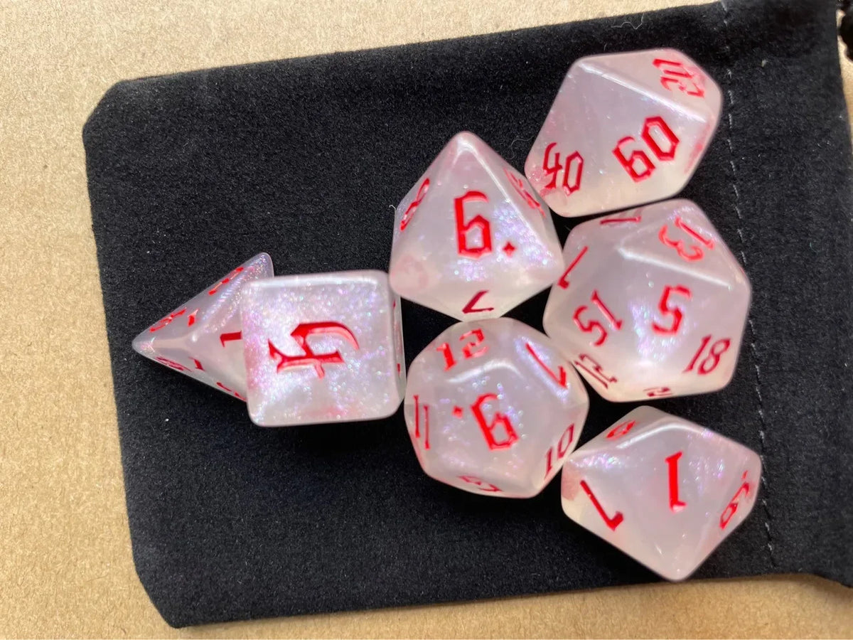 A set of seven pink glitter polyhedral dice resting on a black felt surface.