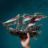 A hand holds a detailed steampunk pirate ship 3D wooden puzzle model kit against a dark teal background.
