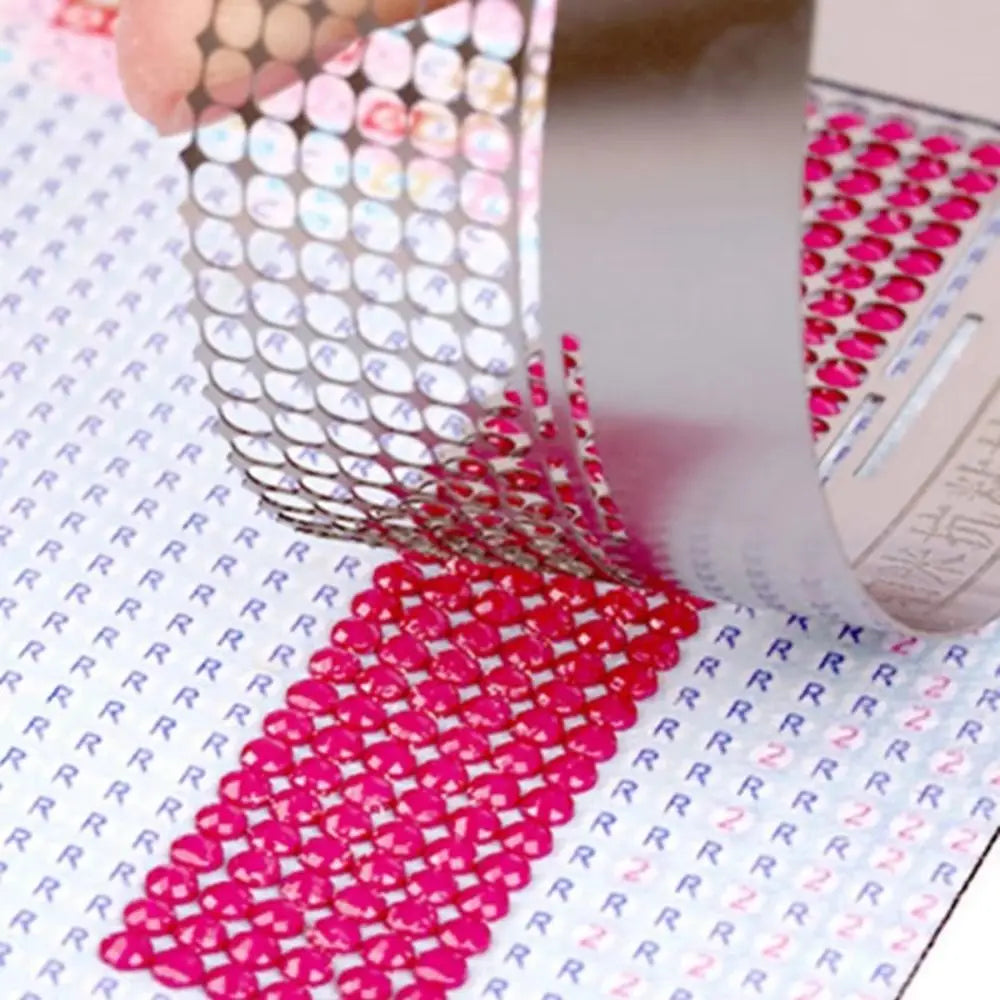 Stainless steel cross ruler used for diamond painting, showing a close-up of the tool and pink beads.