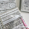 A close-up of a sheet of gray and white lace patterned sticker paper being cut with a precision craft knife.