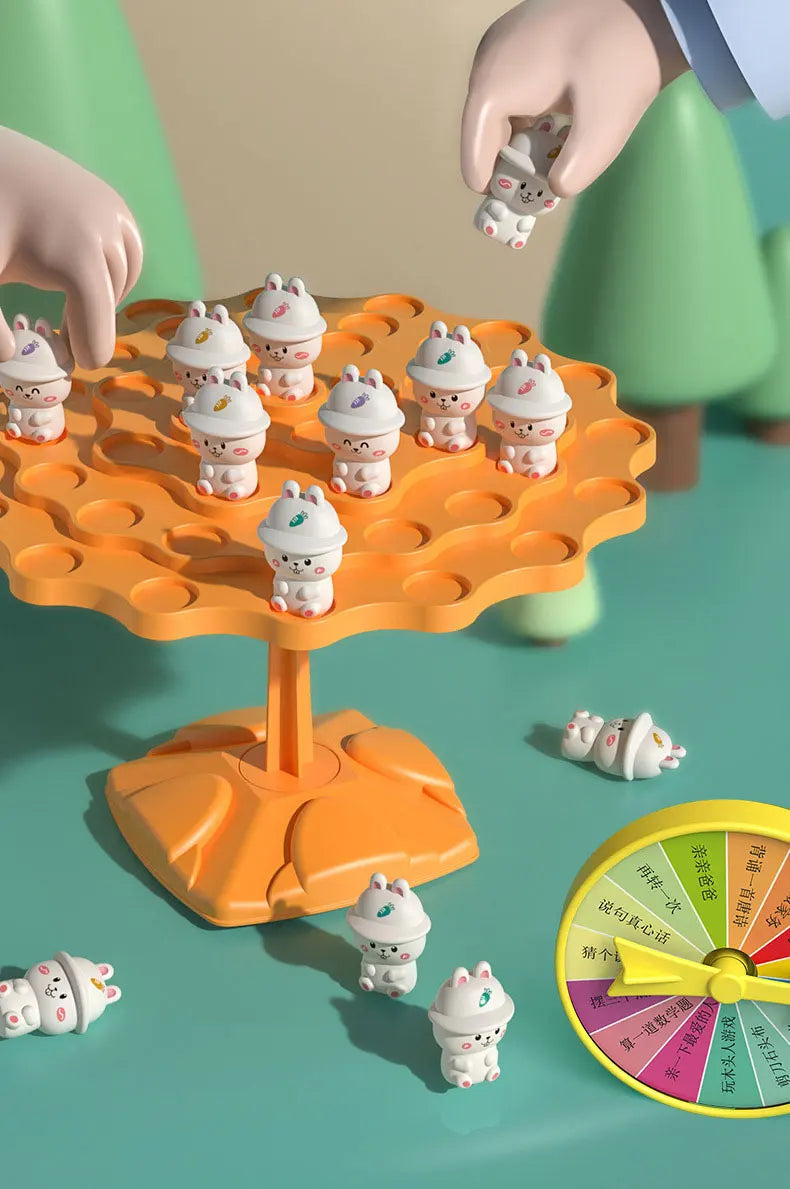 An orange plastic tree game with small white frog figures, showing a hand placing a frog onto the tree.