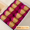 A box of Merino wool yarn balls in magenta and gold labels, packaged for knitting projects.