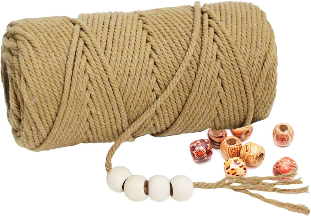 A large spool of natural beige cotton macrame rope with a loose end and several small decorative beads.