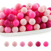 A pile of round silicone beads in various shades of pink and magenta for jewelry making