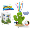 A green cactus sprinkler toy with orange and blue water tubes is shown next to its packaging.