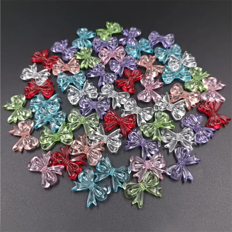 A scattered collection of 20 colorful acrylic bow beads in various shades of pink, purple, blue, and green.
