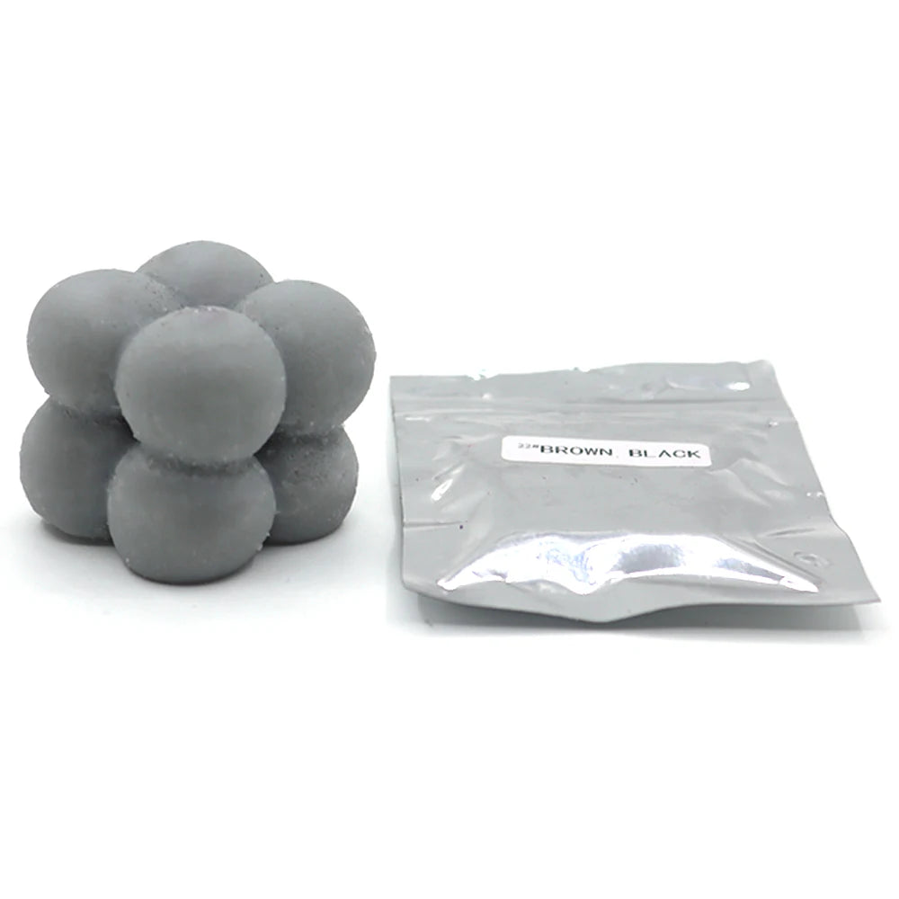 A pile of gray candle dye chips in a sealed plastic bag labeled brown black