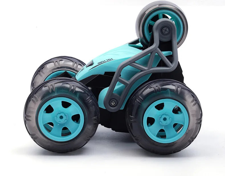 A teal and black remote control stunt car with five wheels is shown from the side.