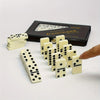 A set of double six dominoes game pieces in white and black dots displayed next to the original box.