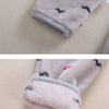 A close-up of a gray fleece jacket and pants set with black cartoon animal prints on a light background.