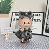A plush Labubu doll wearing a black flannel outfit with a bow, displayed in front of a framed sign.