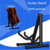 A black foldable metal guitar stand shown next to a display of an acoustic guitar.