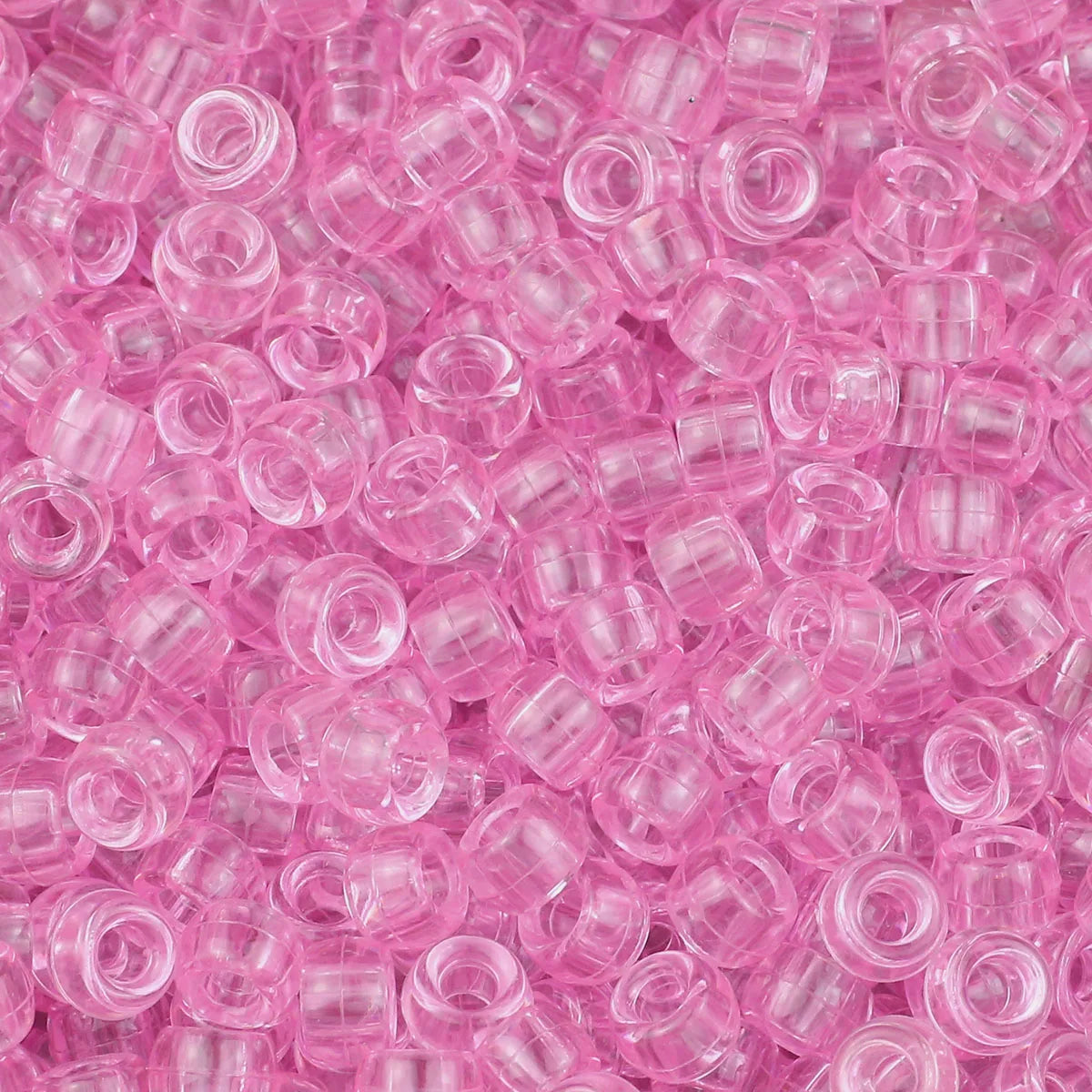 A close-up view of small, translucent pink pony beads for jewelry making and craft projects.