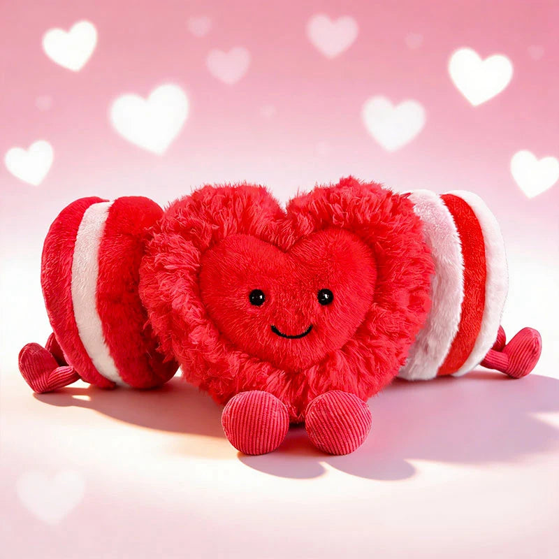 A bright red and white striped heart-shaped plush cushion with a smiling face against a pink background.