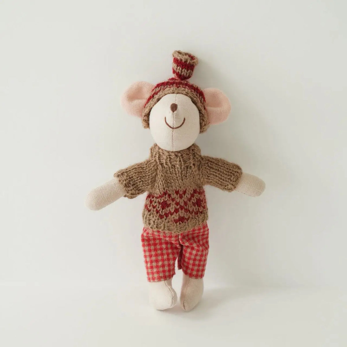 A handmade mouse plush doll wearing a knitted outfit with a red and white checkered top and red shorts.